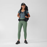 a girl is standing wearing branded & durable green slim fit women trousers and fjallraven 1960 logo hat and a hooodie with backpack on her back.