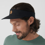 a men is wearing branded visor summer black cap with fox logo and smiling.