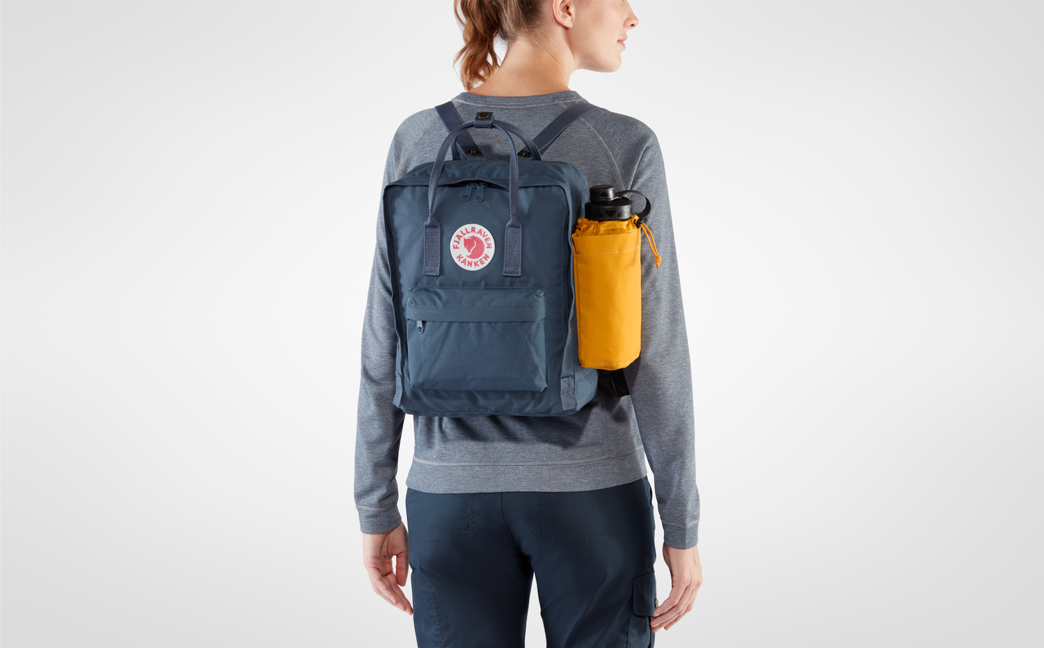 a girl using kanken bottle pocket160 Ochre for her kanken backpack
