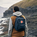 a man trevelling outdoor with carring fjallraven kanken laptop backpack in graphite colure on his back