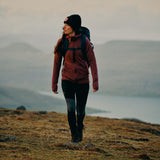 a girl is walking wearing branded & durable black slim fit women trousers and fjallraven 1960 logo hat and a hooodie with backpack on her back.